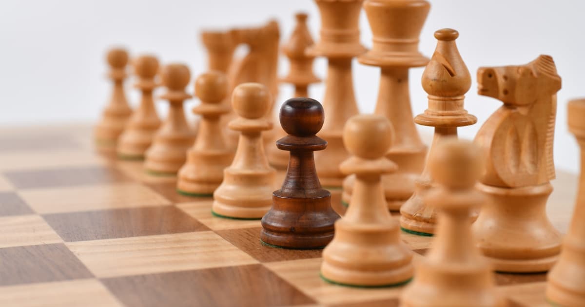 Chess player contemplating next move, representing strategic decision-making over busy execution