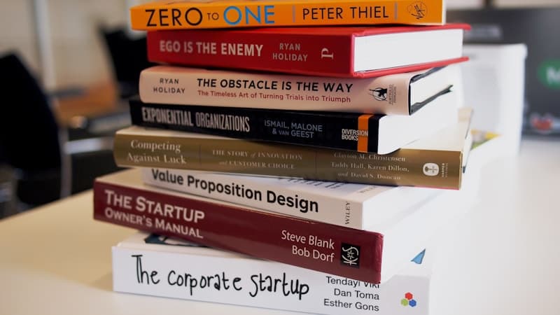 Stack of seven well-worn non-fiction books with sticky notes marking passages